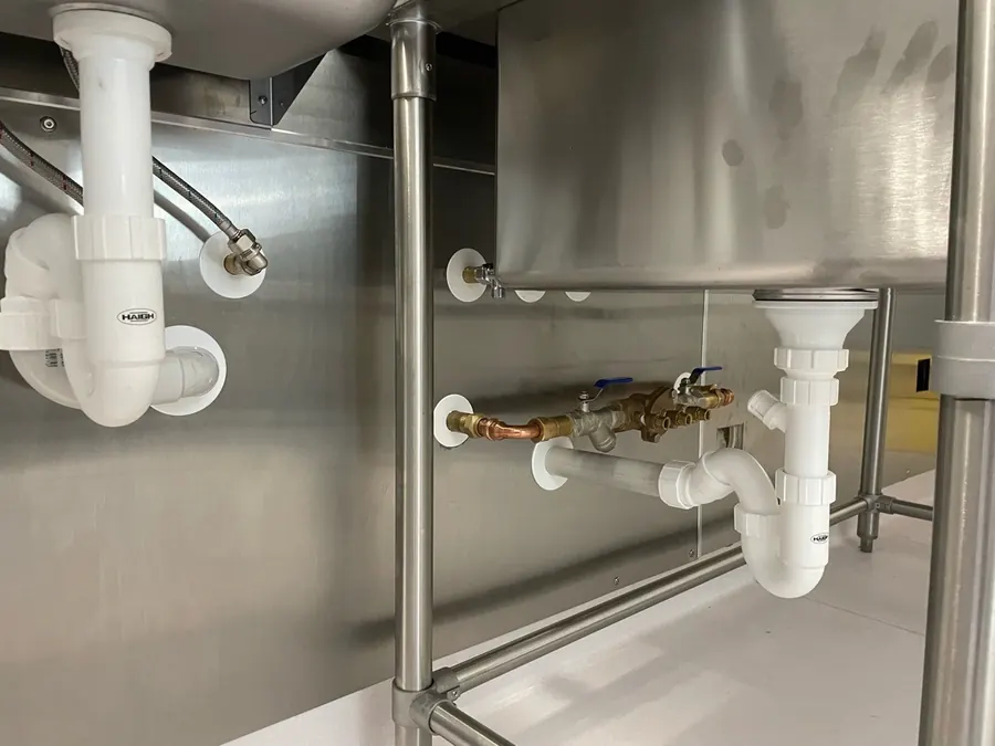 A double check backflow valve on the water supply under a stainless steel sink