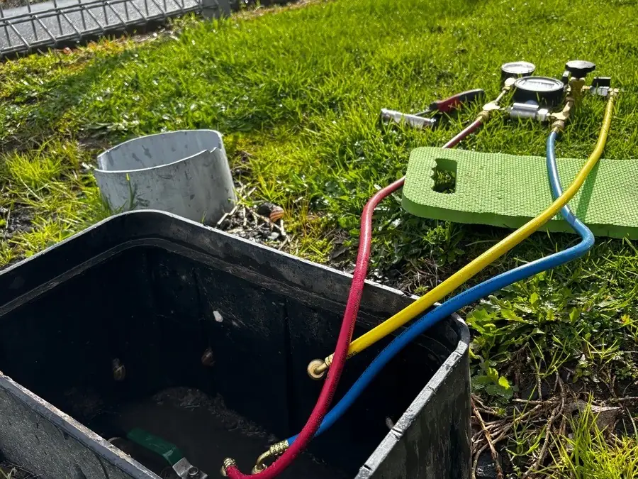 Test gauges connected by red, yellow and blue hoses to a backflow device in a ground box
