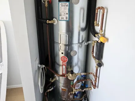 A new mains pressure hot water cylinder in a cupboard, with copper pipework, valves and lagged wetback pipes