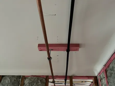 New copper and plastic water pipes run neatly along the ceiling on timber supports