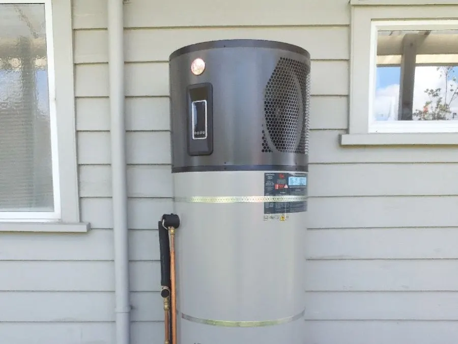 A new heat pump hot water system installed against a weatherboard house