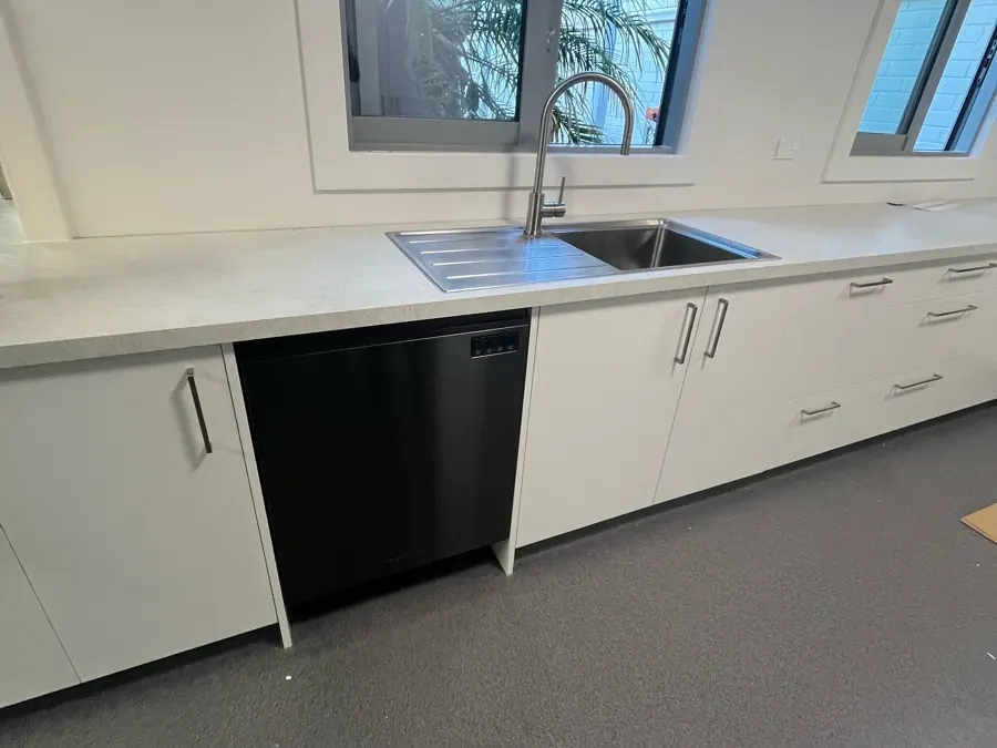 A finished staffroom kitchen with a new benchtop, sink, mixer and dishwasher