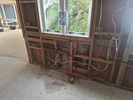 The kitchen wall stripped back to the framing, with new water pipework roughed in