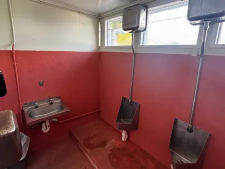 The old toilet room in the block, with wall basin and urinals, before the strip-out